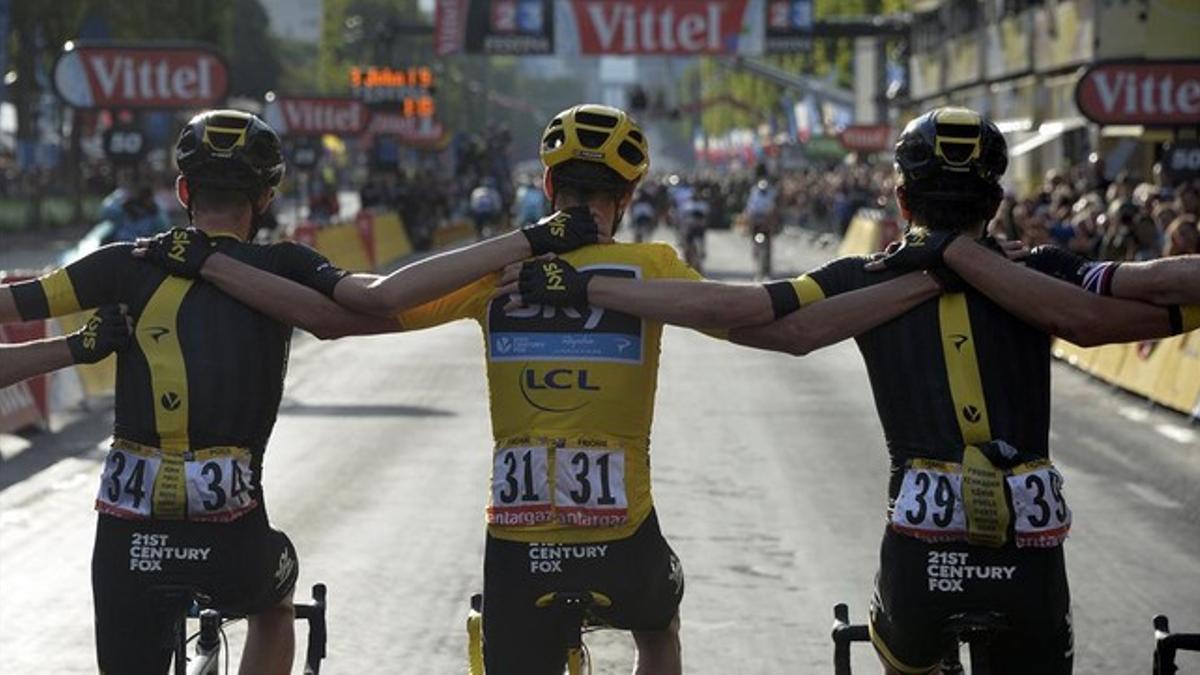 Chris Froome, a punto de cruzar la última meta del Tour 2015 abrazado a sus compañeros del Sky.