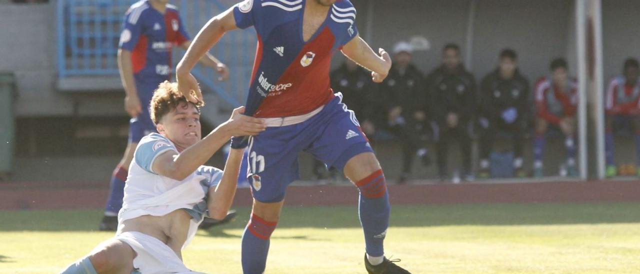 David Iglesias conduce el balón ante un defensor del Compostela, que le agarra. | Área 11