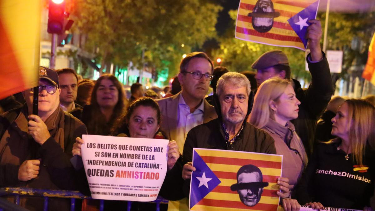 Una bandera estelada amb la cara de Pedro Sánchez tatxada i un cartell contra l&#039;amnistia durant les protestes davant la seu del PSOE al carrer Ferraz de Madrid
