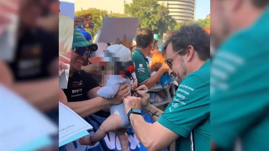 Fernando Alonso firma un autógrafo en un bebé durante el GP de Barcelona