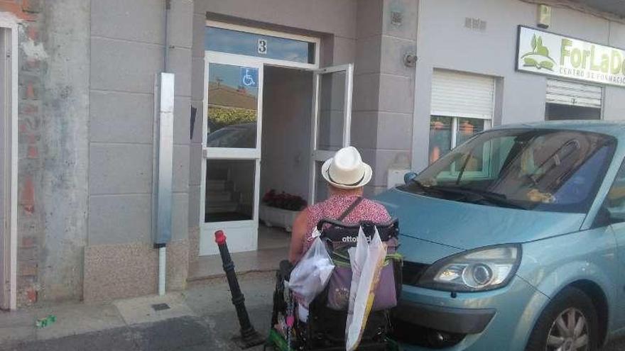 La mujer discapacitada espera para entrar al portal de la vivienda.