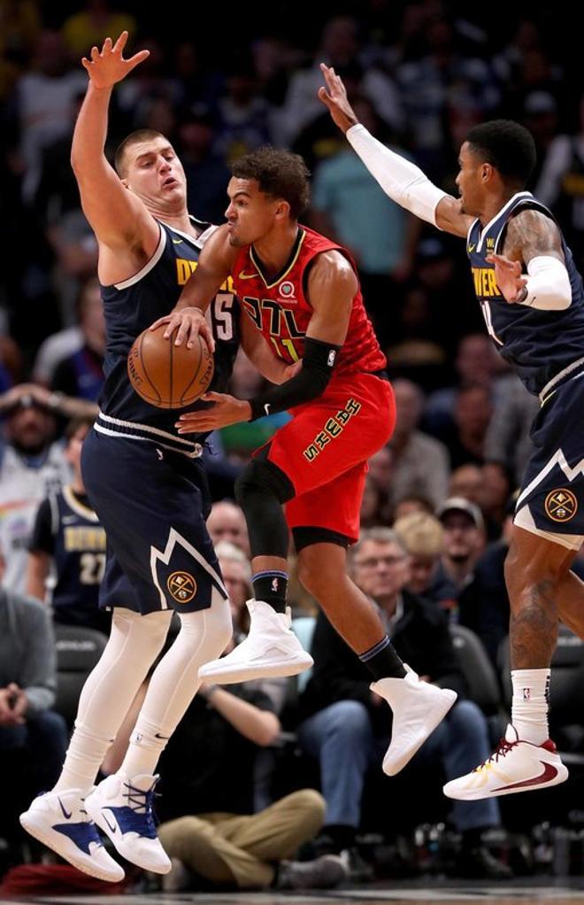 Trae Young # 11 de los Atlanta Hawks conduce contra Nikola Jokic # 15 y Gary harris # 14 de los Denver Nuggets en el último cuarto en el Pepsi Center en Denver, Colorado.