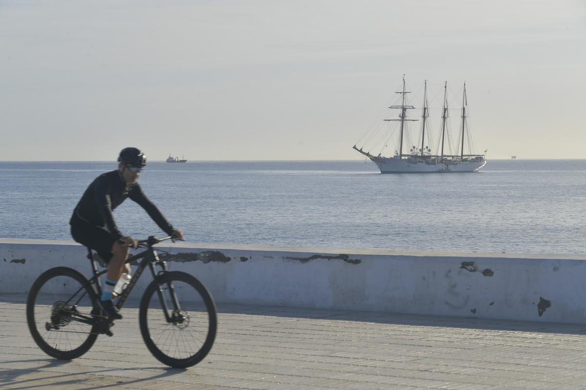 Un ciclista pasa por la avenida Marítima, con el 'Juan Sebastián de Elcano' al fondo.