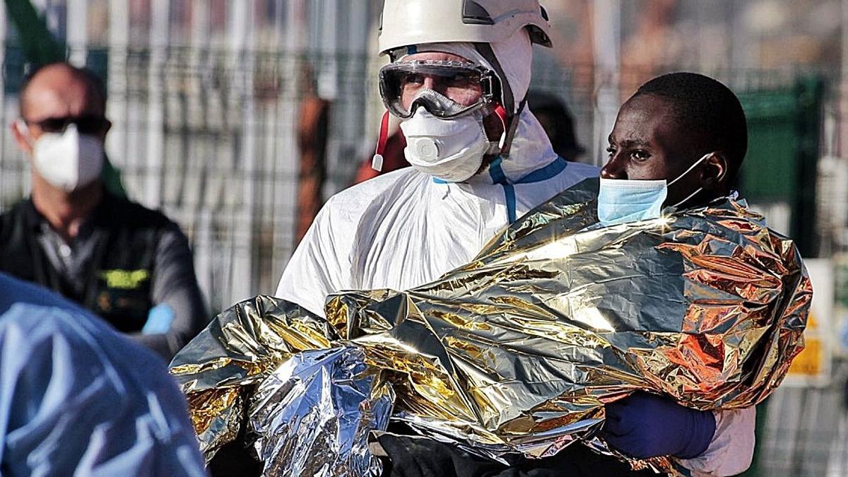 Uno de los migrantes, ayer, en brazos de un miembro del equipo de rescate.