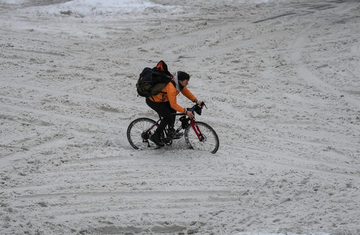 Un ciclista se abre paso entre la nieve en la calle Robson en un día de intensa lluvia en el centro de Vancouver, Canadá