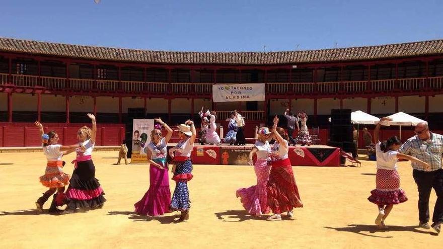 Varios asistentes bailan sevillanas en la plaza de toros.