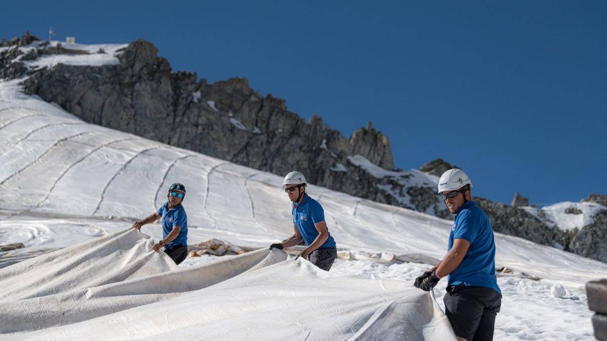 Operarios extendiendo una manta sobre el glaciar italiano