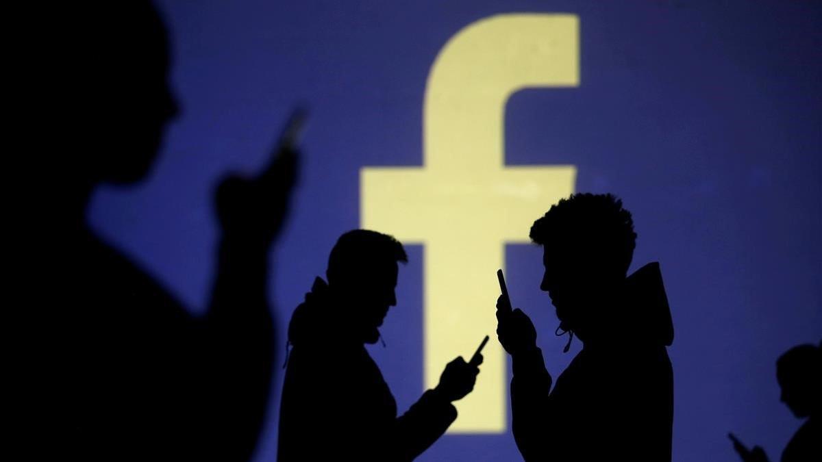 Usuarios de móvil ante el logo de Facebook.