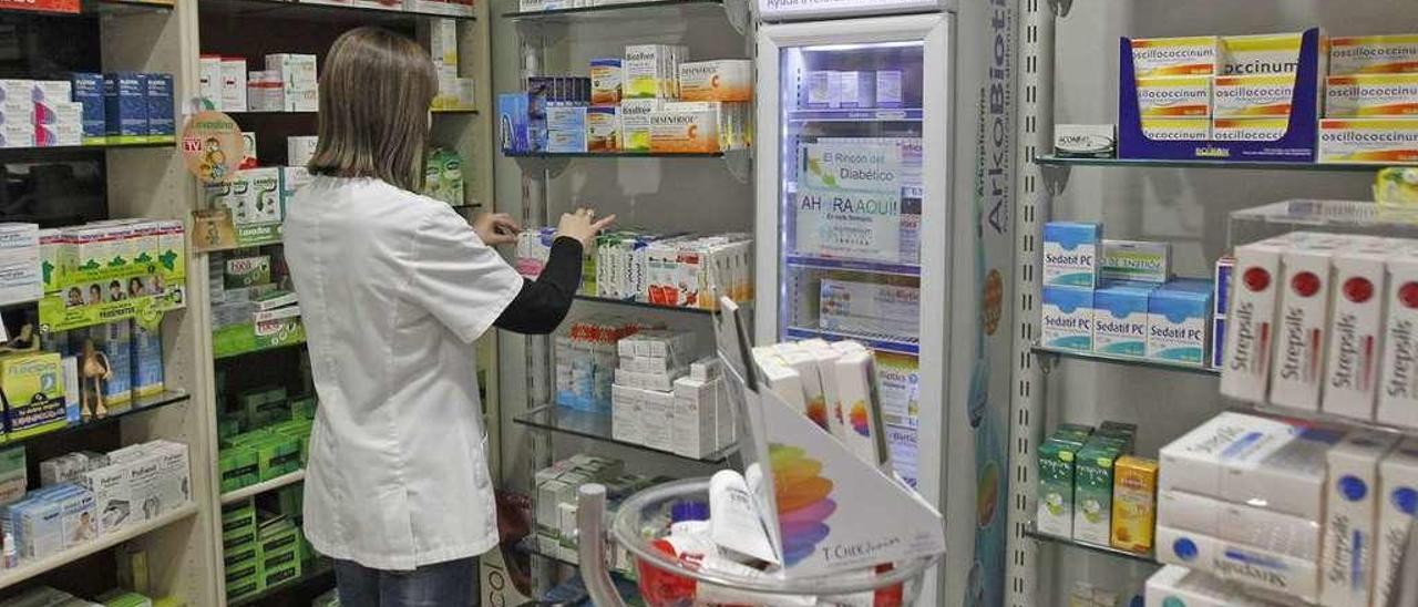 Una trabajadora de una farmacia revisa los productos de su establecimiento en Ourense