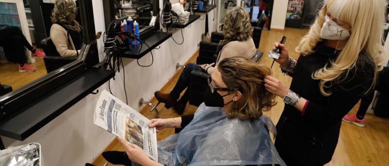 Isabel Soria atendiendo en su peluquería a Begoña García.