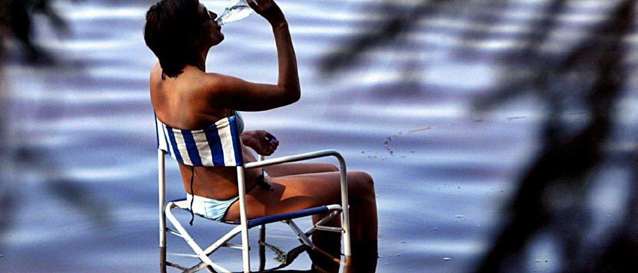 Una mujer bebe de una botella de agua para refrescarse durante una ola de calor.