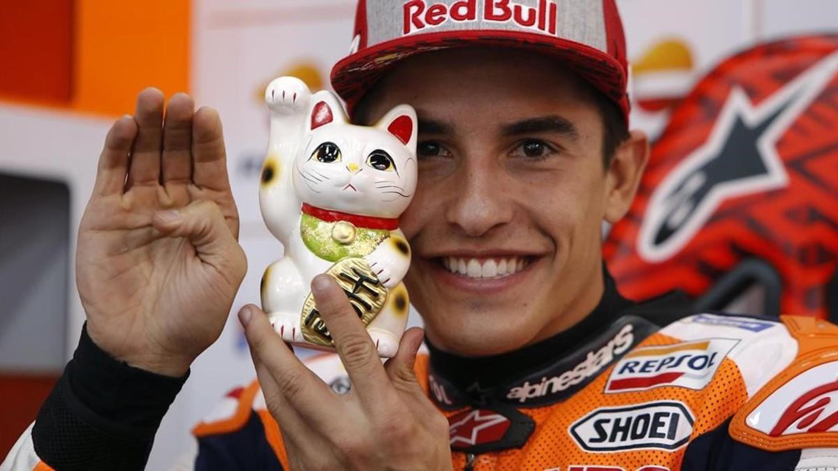 Marc Márquez muestra a su gato de la suerte japonés, al que tiene junto a él en el box del equipo Repsol Honda, en Motegi (Japón).