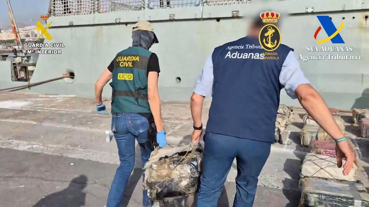 Una agente de la Guardia Civil y uno del SVA descargan fardos de droga incautados en el remoclador Sky White en agosto pasado