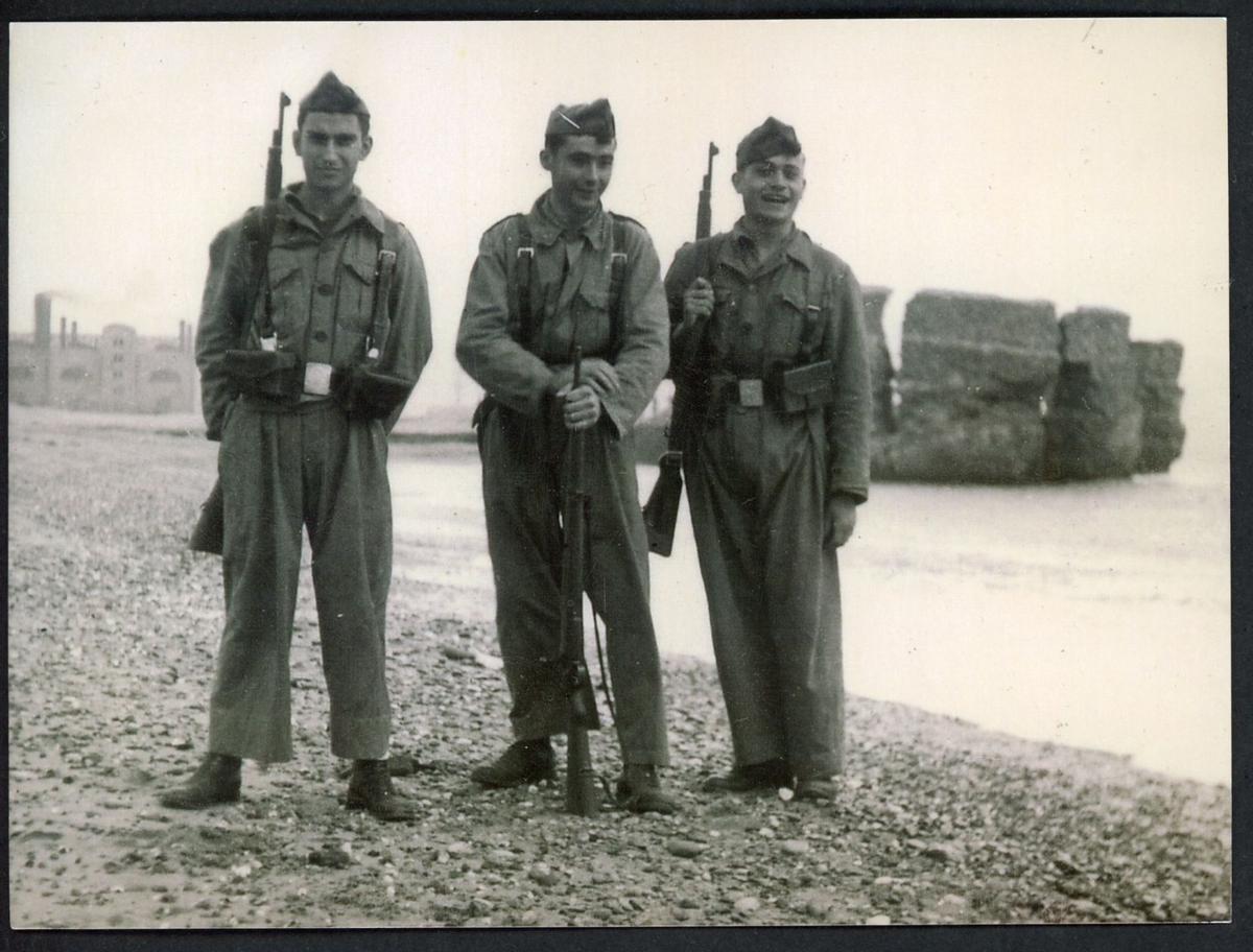 Tres soldados del Regimiento de Caballería Numancia posan en el Camp de la Bota y, tras ellos, el paredón, del que los ajusticiados caían directamente sobre el mar.