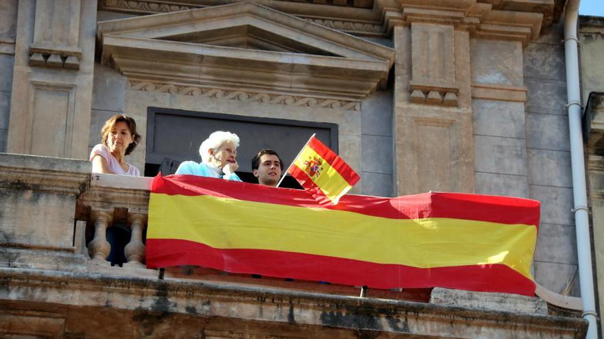 Unes persones exhibeixen una bandera espanyola en un balcó