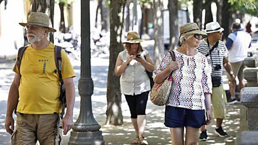 Turistes amb barrets per aguantar el sol, ahir, a Girona.