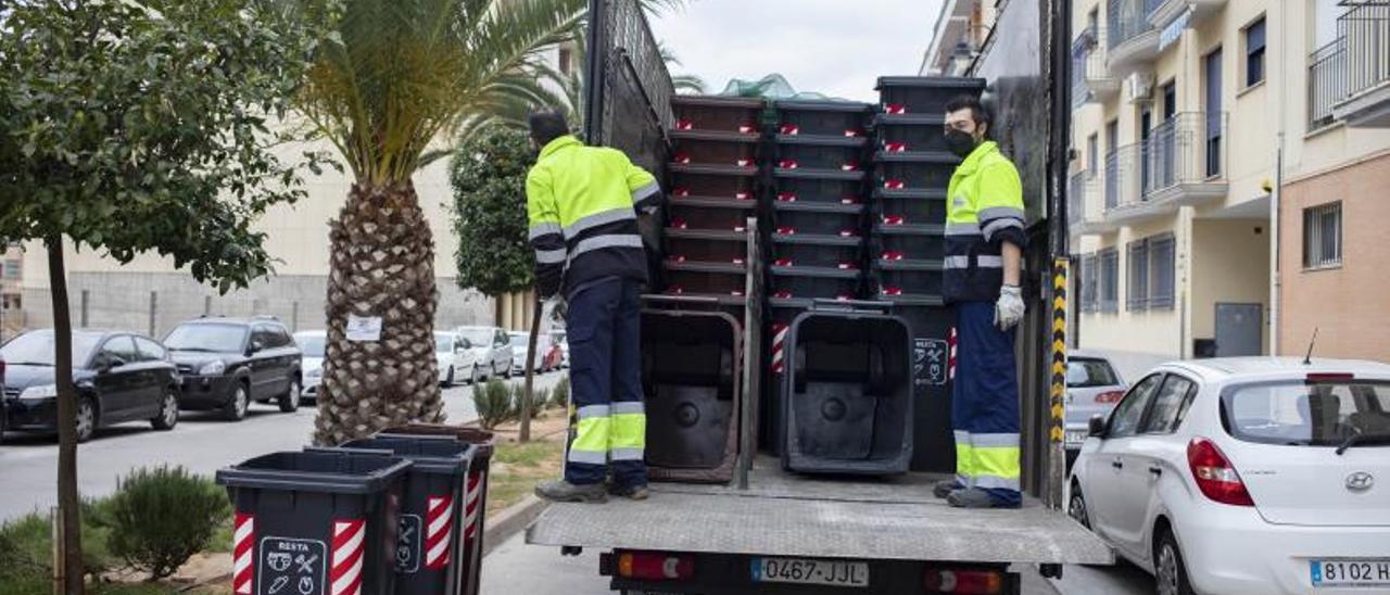 Dos operarios colocan los contenedores en la calle | PERALES IBORRA