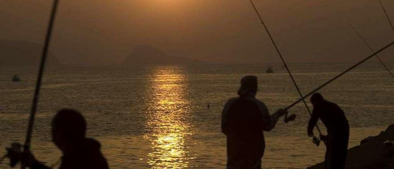 Pescadores durante la puesta de sol en la bocana de la ría de Avilés.