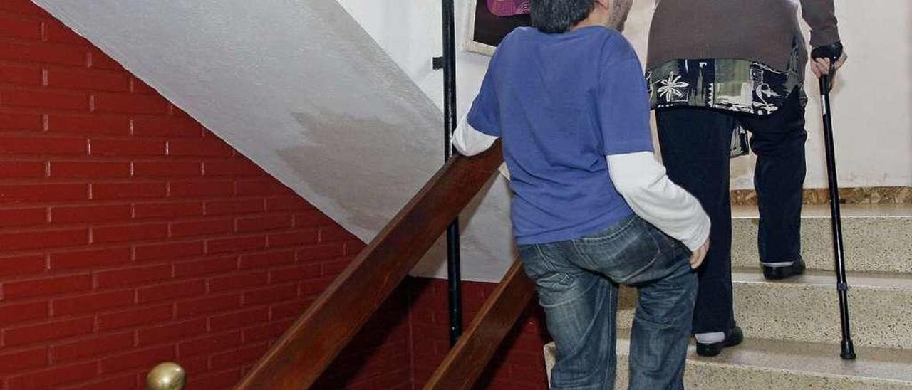 Vecinos suben por la escalera en un edificio en Vigo por falta de ascensor. // Marta G. Brea