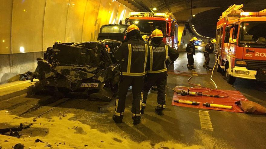 Los bomberos, junto al coche siniestrado.