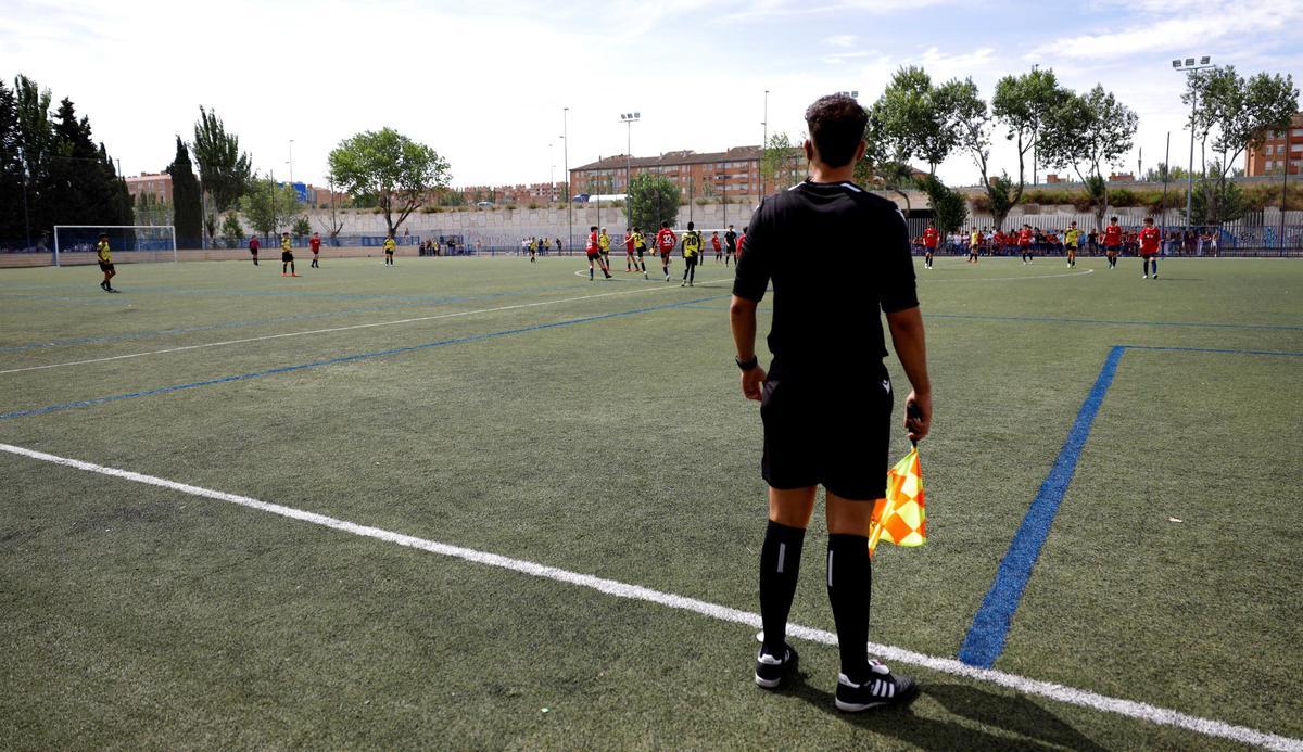 Un juez de línea arbitra un partido de fútbol base en Aragón.