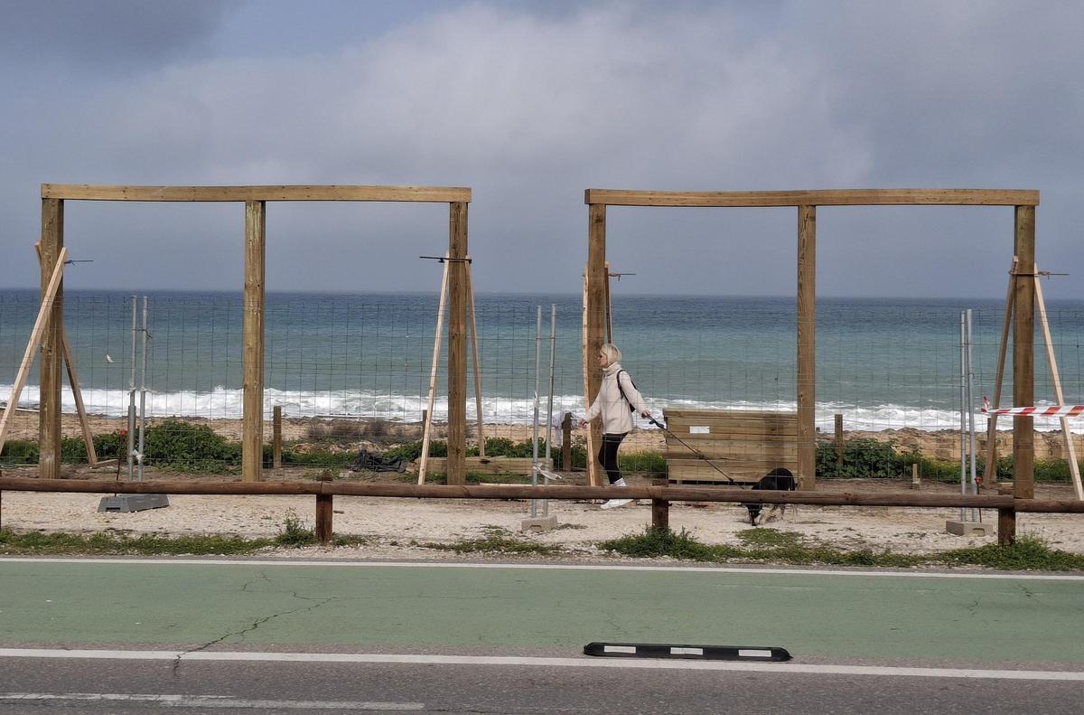 Una vecina pasa ante las estructuras de madera