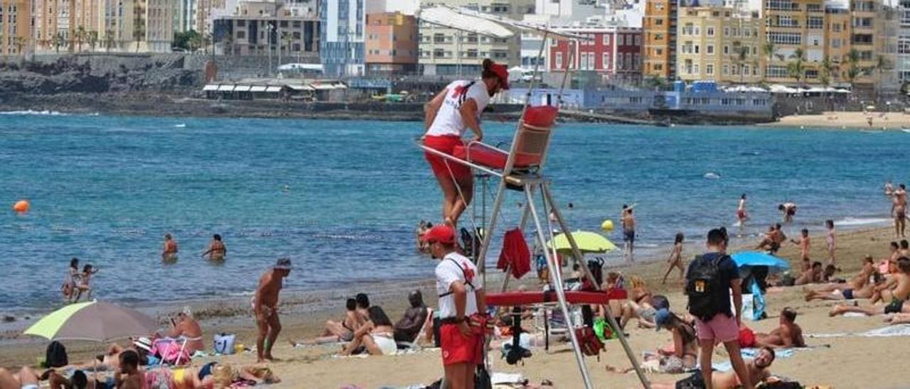 Dos socorristas de la ciudad en una de las sillas metálicas en la playa de Las Canteras