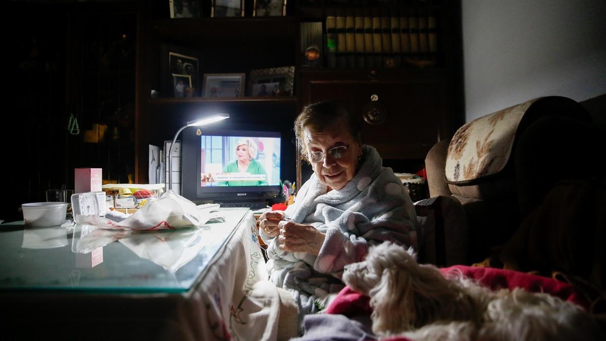Cristi Morte Teje en su hogar con la televisión de fondo y su querido perro. Ella vive sola, aunque recibe visitas de su familia.