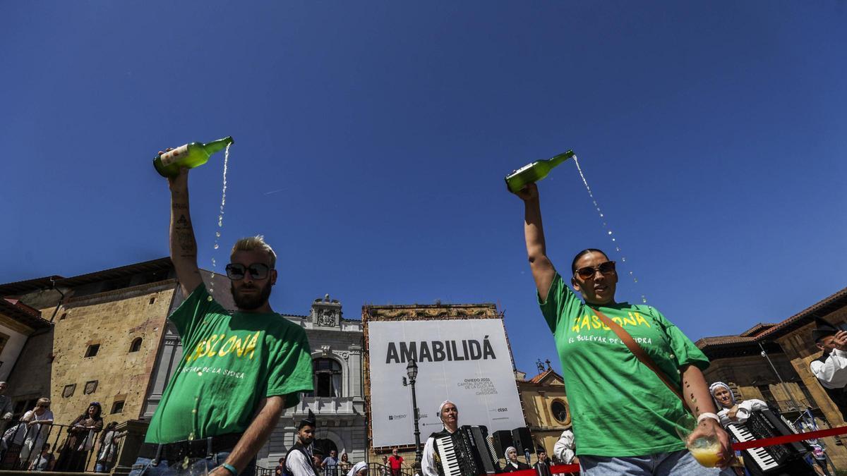 Dos escanciadores con el lema de la "amabilidá" de fondo.