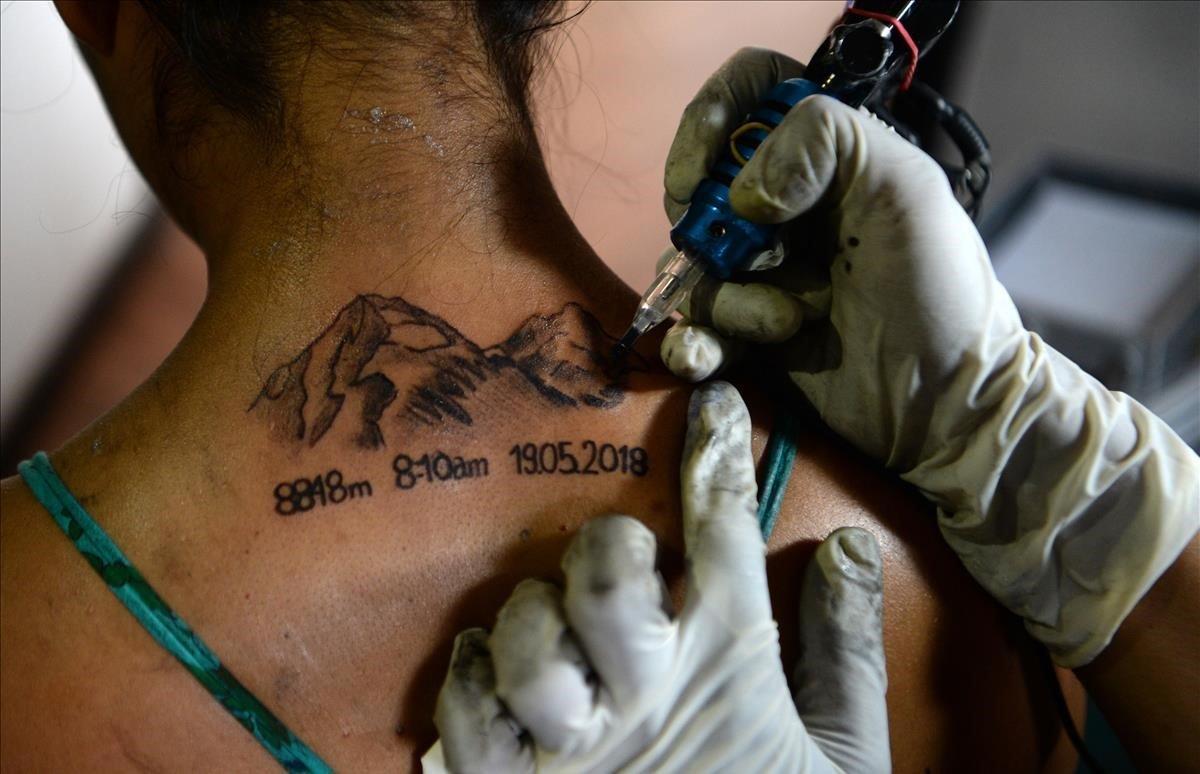 Un tatuador da los toques finales a un tatuaje del Monte Everest en la espalda del fotoperiodista Purnima Shrestha en el 12º Día Internacional del Everest, en Katmandú.