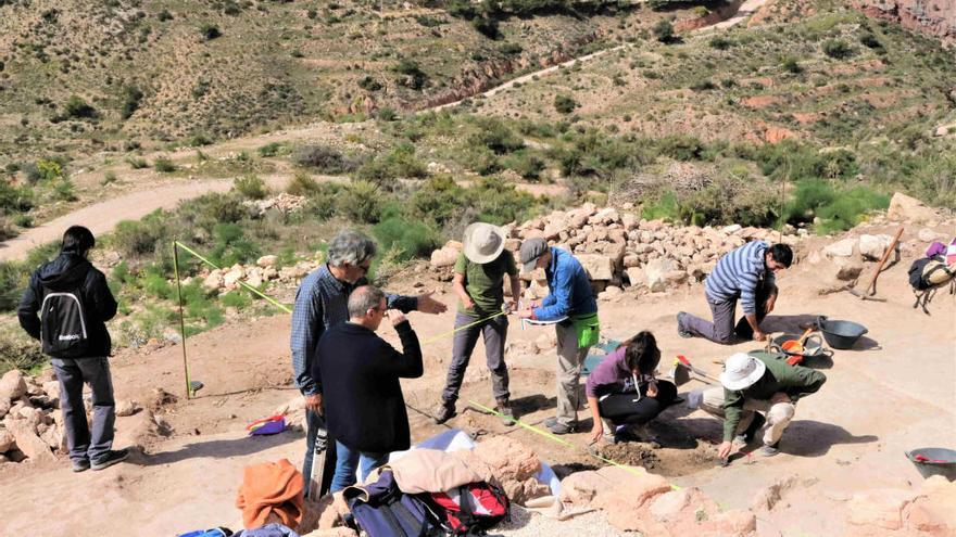 Un grupo de estudiantes de Arqueología hacen prospecciones junto a un edificio de culto guiados por el director de las excavaciones, Alberto Lorrio, y el arqueólogo municipal, Julio Trelis.