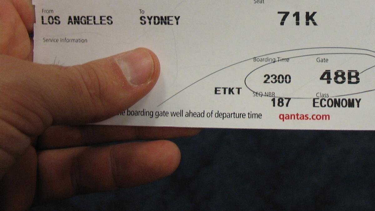 Una persona muestra un billete de avión de Los Ángeles (EEUU) a Sídney (Australia).