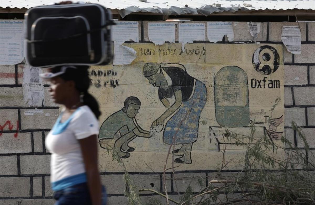 Una mujer en Haití, frente a un mural de Oxfam. 