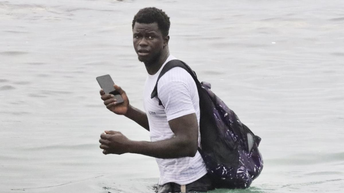 Un inmigrante intentando cruzar la frontera de Ceuta, ayer.