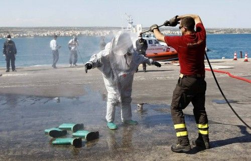 Un bombero limpia a su compañero después de desembarcar de un barco de inmigrantes en el que se encontraron 30 cuerpos, después de que la marina italiana lo remolcase hasta el puerto siciliano de Pozzallo, en Italia.