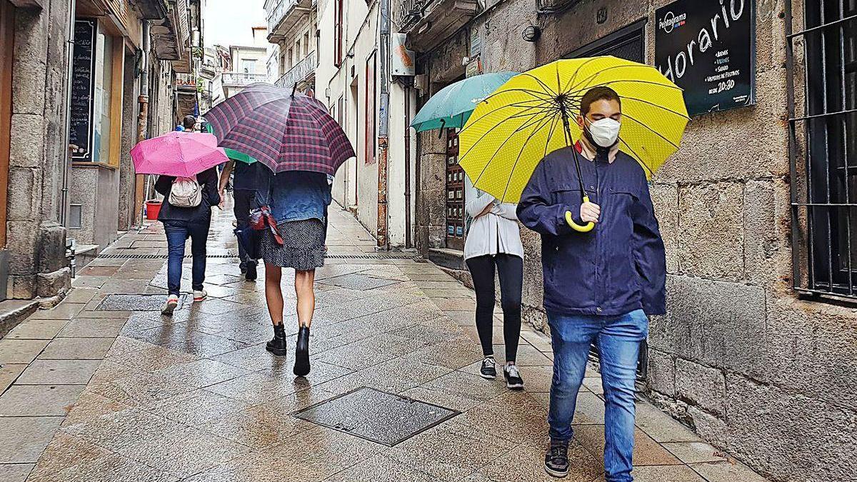 Varias personas, paseando con paraguas por una calle del centro de Vigo, ayer.