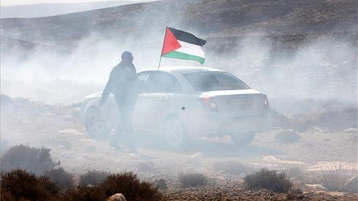 Un hombre ondea la bandera palestina entre gas lacrimógeno en 2019.