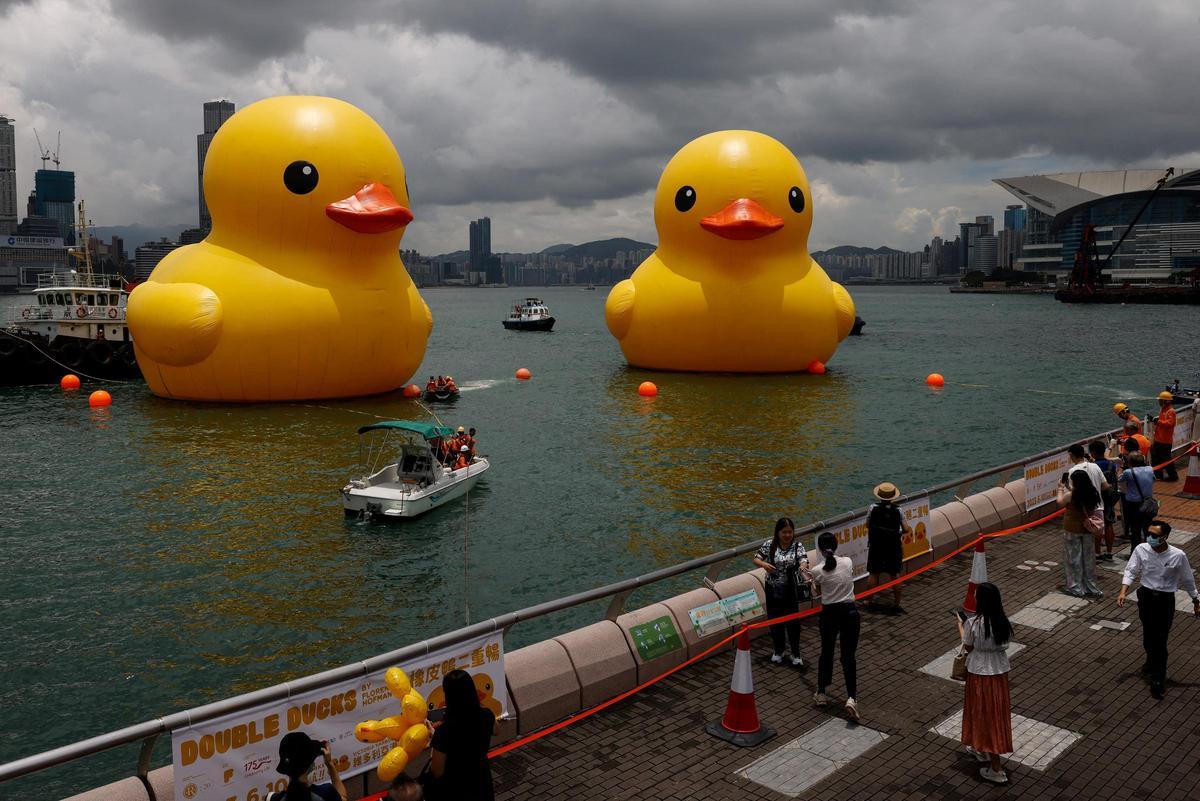 La gente toma fotos de una instalación de arte, apodada "Double Ducks" por el artista holandés Florentijn Hofman, vista en el puerto de Victoria, en Hong Kong.