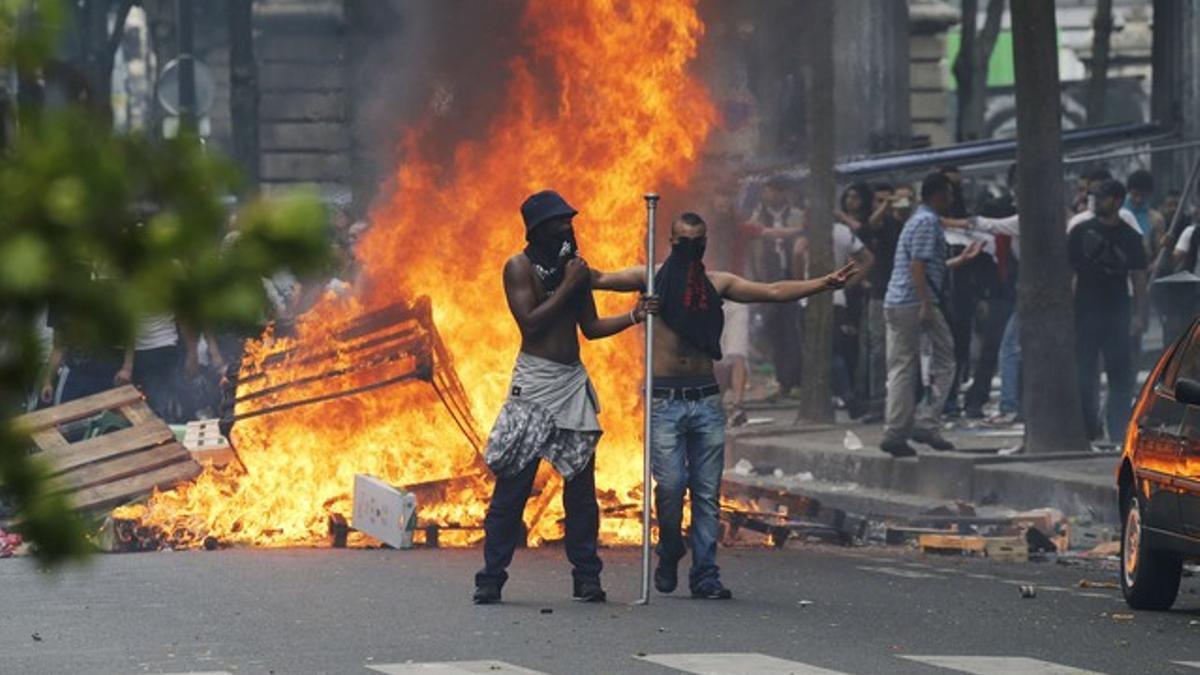 Dos manifestantes, ante una barricada en llamas, durante los enfrentamientos con la policía.