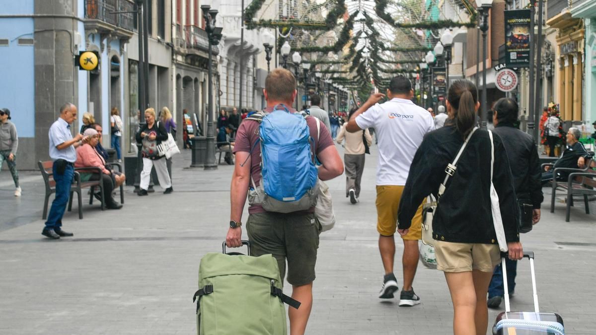 Varios turistas pasean con sus maletas por Triana.