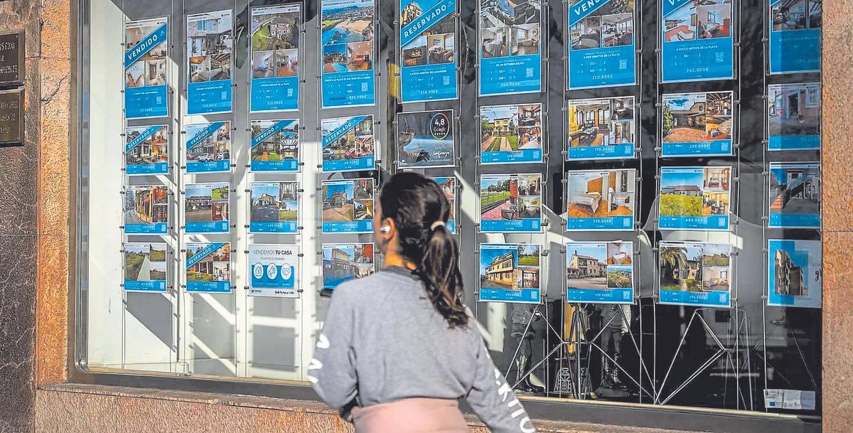 Una joven pasa ante el escaparate de una inmobiliaria.