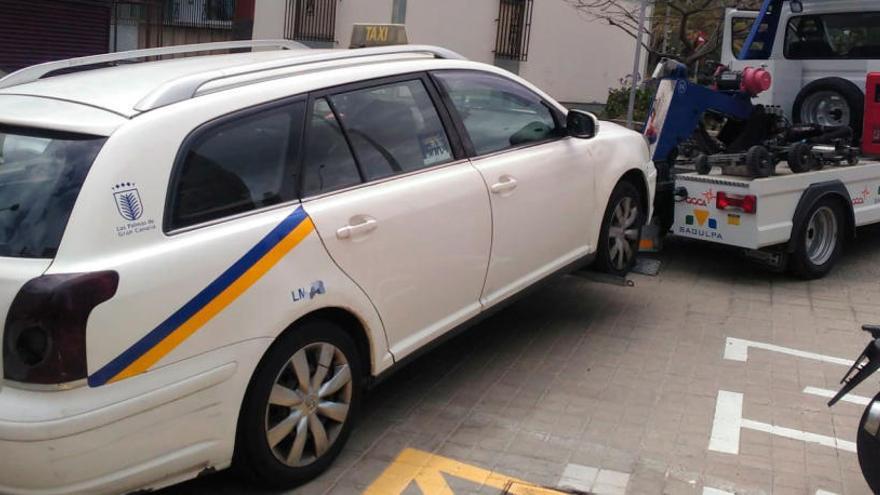 El taxi en el momento que la grúa lo traslada al depósito municipal.