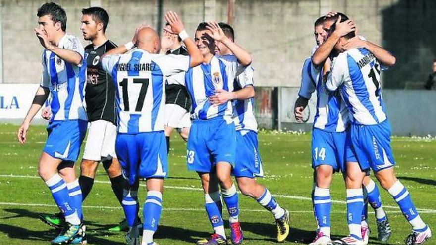 Los jugadores del Avilés celebran el gol de Milio, felicitado por Miguel Suárez, en el centro de la imagen.