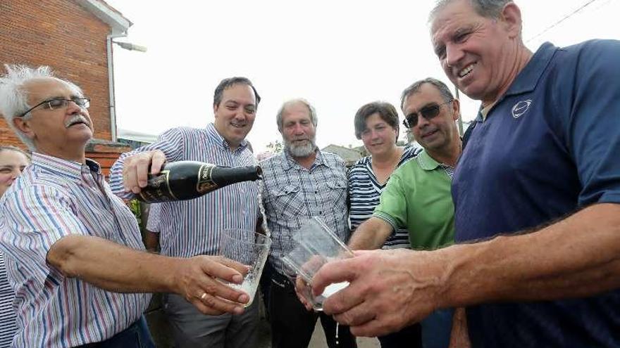 El alcalde de Villaviciosa, Alejandro Vega, sirve sidra a José Manuel Cardín y Loli Riva, a su izquierda, entre otros vecinos.