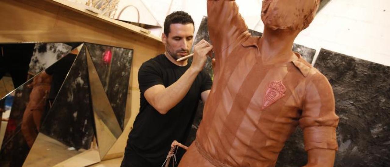 Carlos García, en su estudio rematando la estatua de Quini. A la derecha, la figura con la cabeza de Quini | Á. González