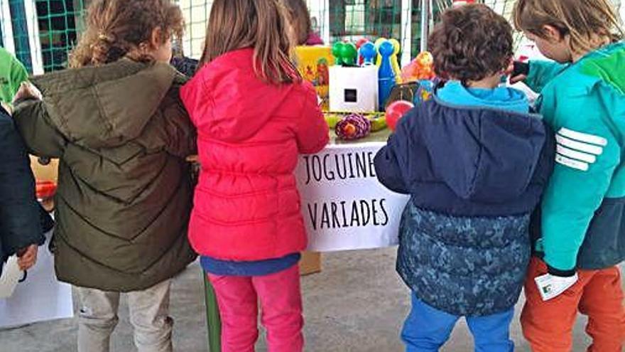 Un grup d&#039;escolars revisant les joguines de segona mà.