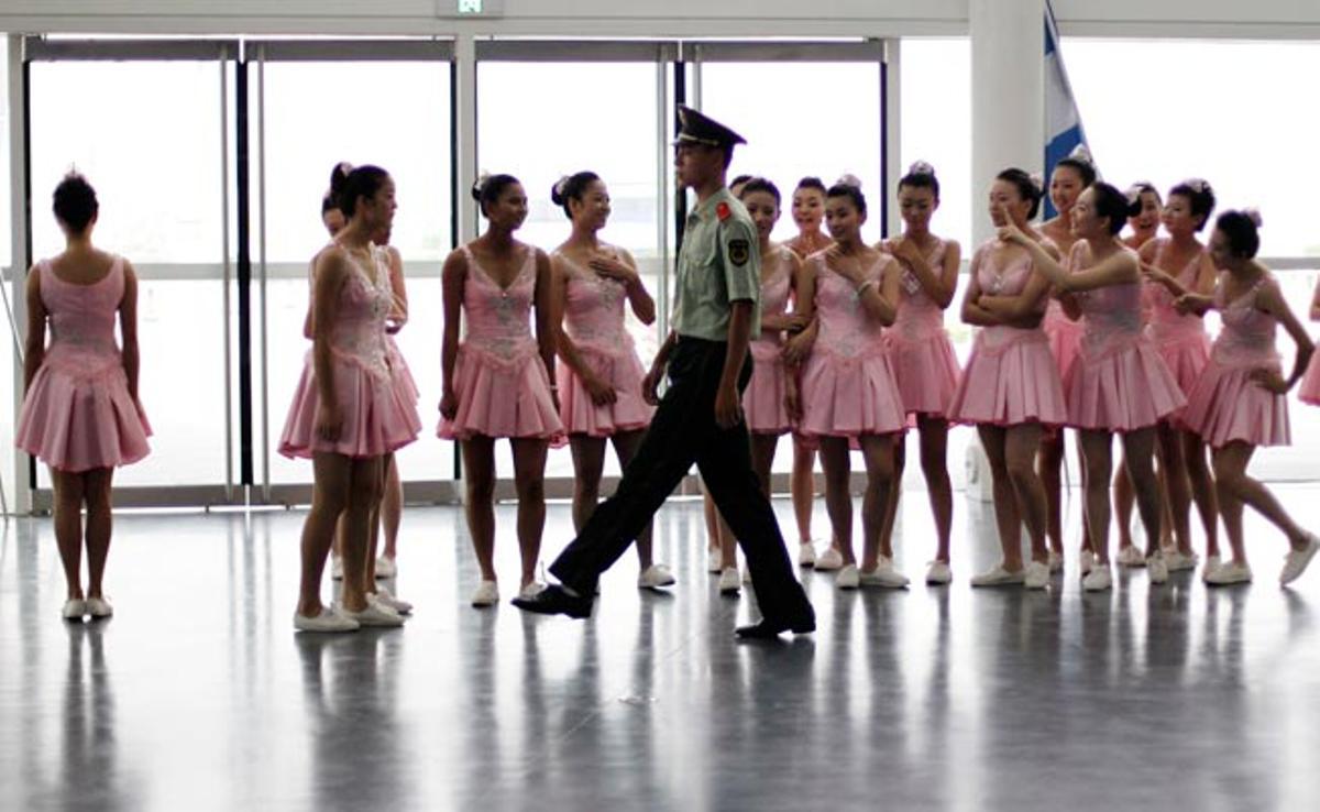 Un oficial xinès mostra com marxar a un grup de ballarines que participaran en l’obertura dels mundials de natació 2011, a Xangai, Xina.