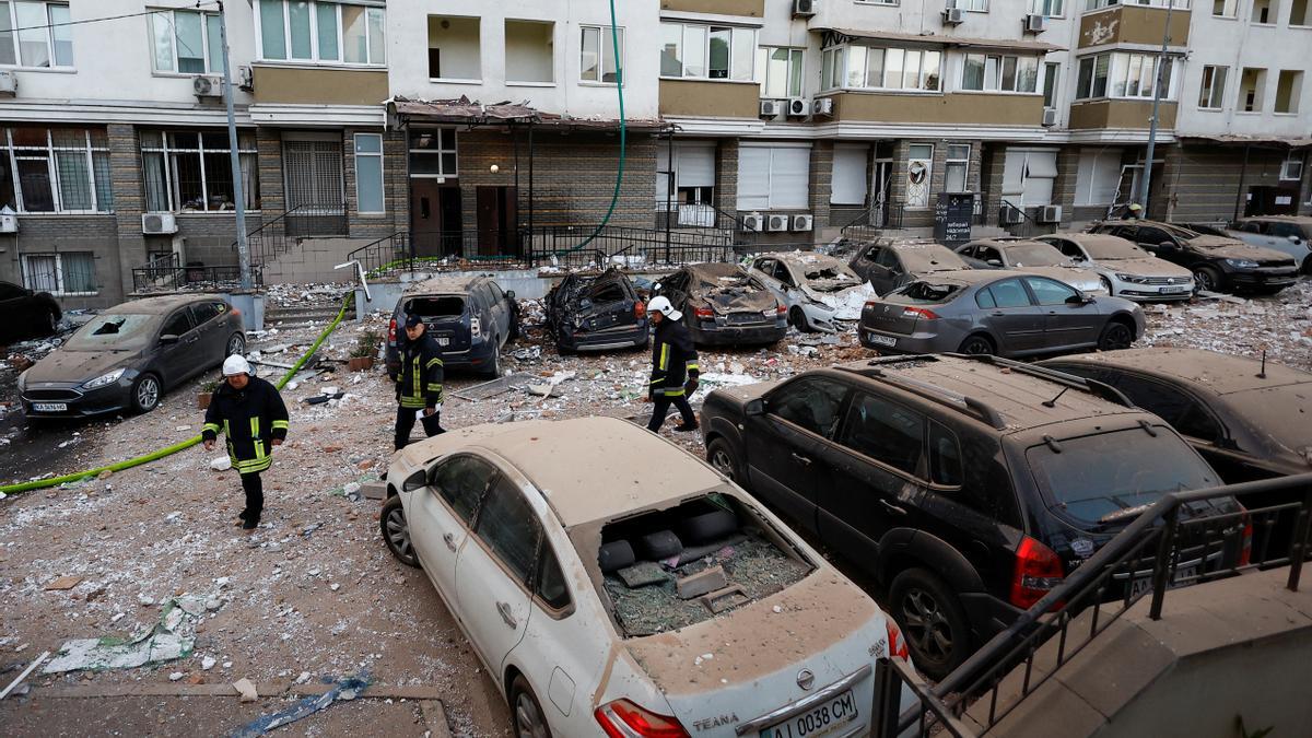 Firefighters work near cars damaged during a massive Russian drone strike, amid Russia’s attack on Ukraine, in Kyiv