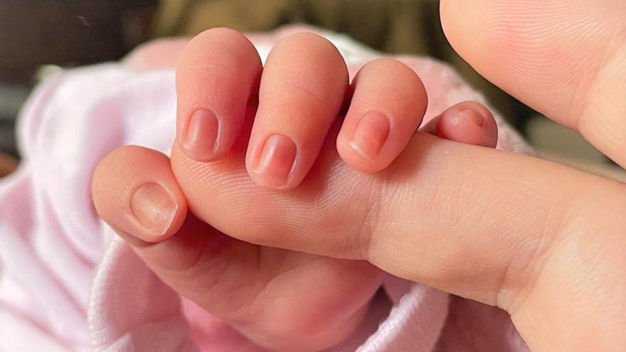 Un bebé de pocos días de edad coge el dedo de su madre.
