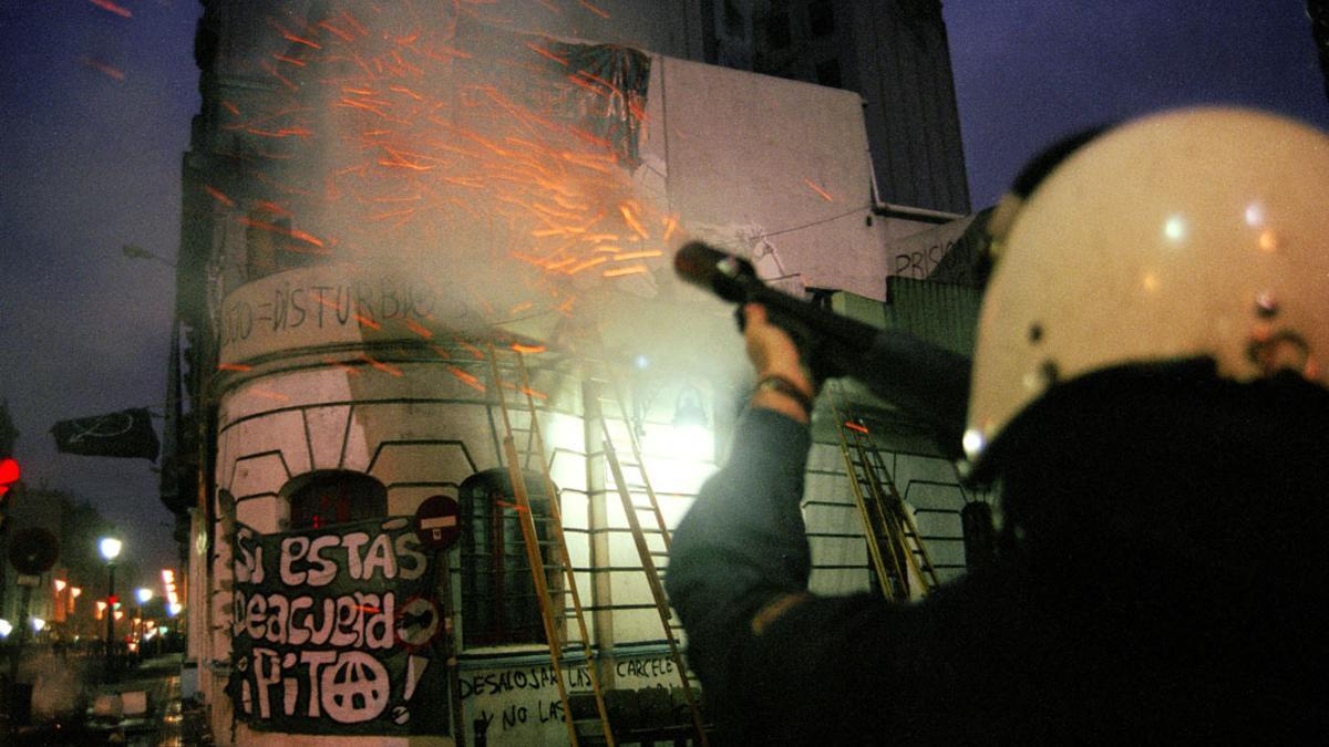 Un policía dispara su escopeta de pelotas de foam durante el desalojo del Cine Princesa en 1996.